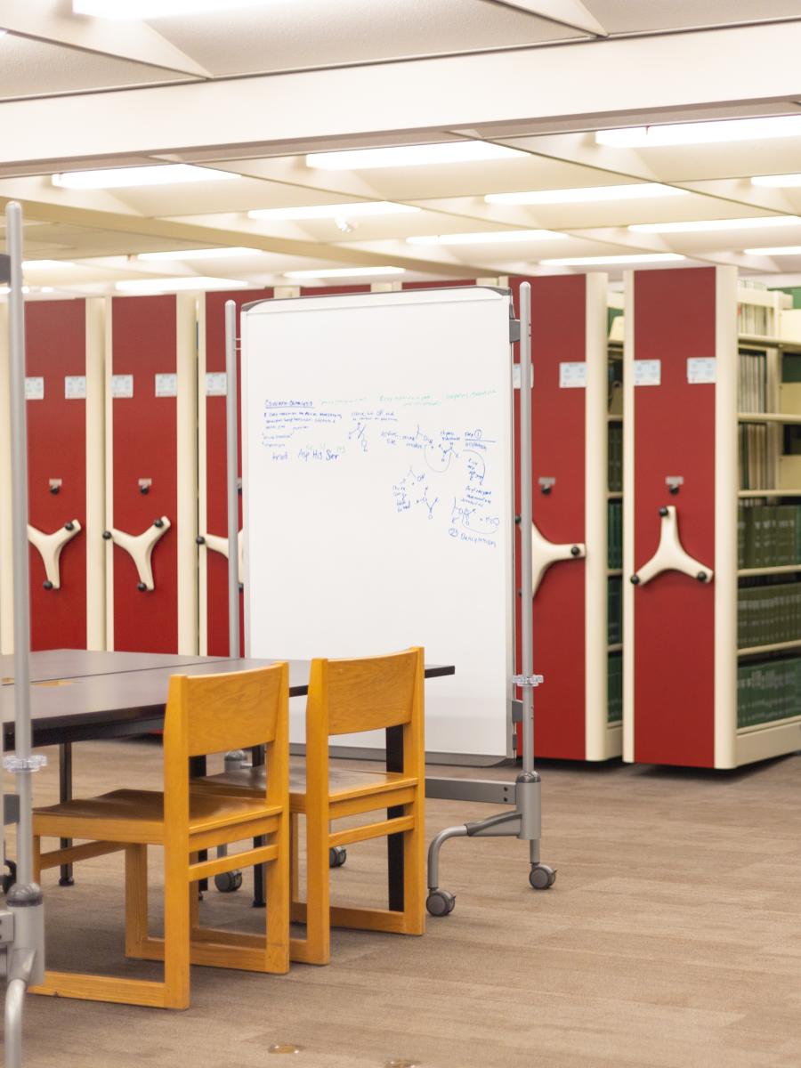 Empty table in front of white board and compact shelving