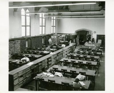 Interior of Dodd hall in black and white. Rows of long tables line either side of cabinets that appear to be card catalogs