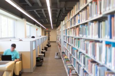 students studying at tables near book shelves