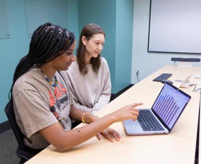two women looking at a graph on a laptop