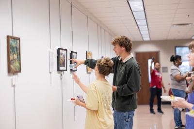 Two people pointing at painting during 200 years of Tallahassee exhibition