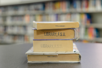 stack of four FSU Library books on a table