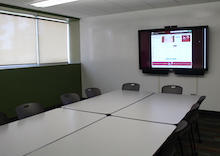 4 tables surrounded by chairs, with a mounted computer