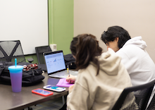 Two people studying off the same material in a group study room