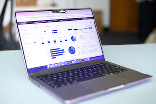 Laptop on a desk displaying a business analytics dashboard with pie charts, bar graphs, and numerical data.