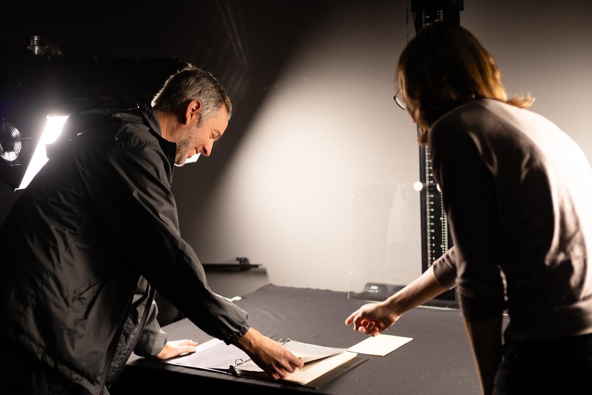 two people standing and looking at documents on a table