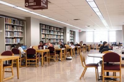 students studying at tables near book shelves